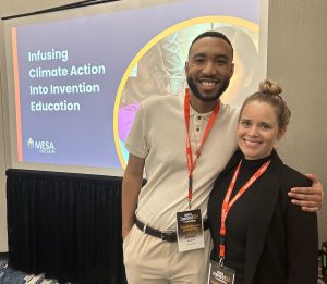 Two smiling people with conference badges stand together in front of a screen displaying "Infusing Climate Action Into Invention Education," showing how MESA Oregon helps in Turning Passion Into Action for positive change.