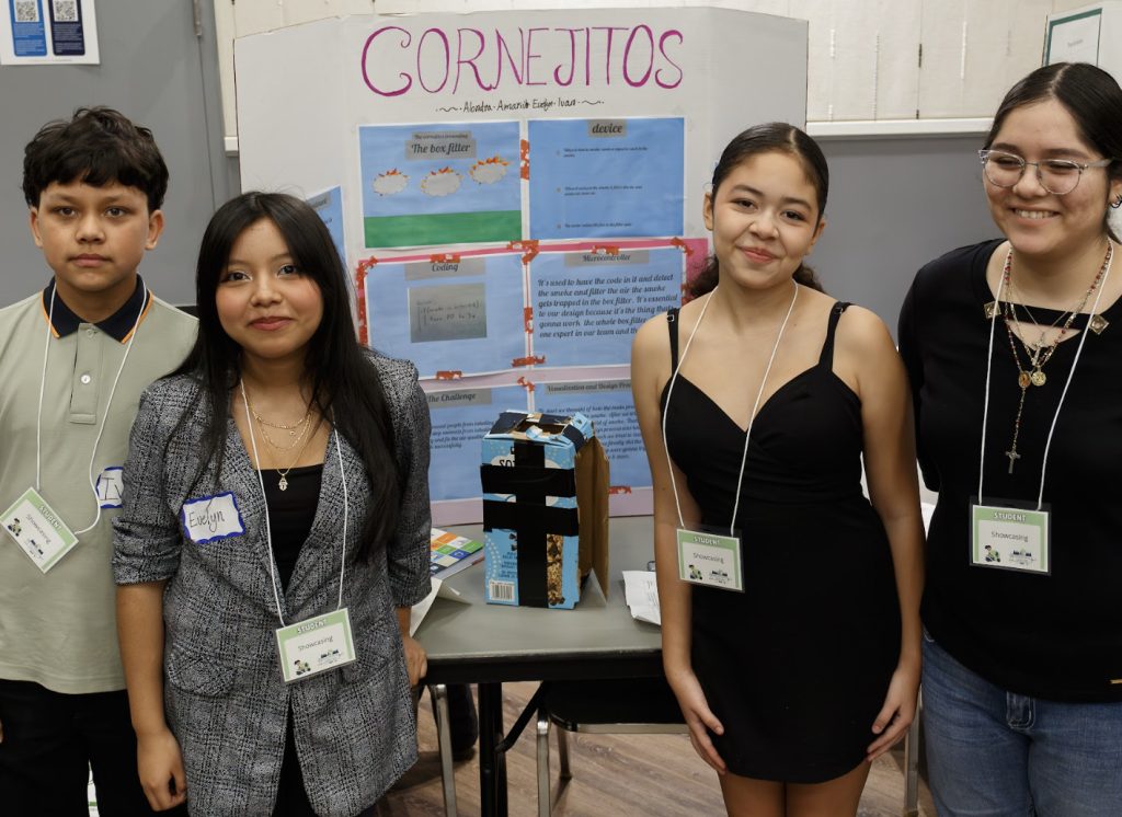 Four students stand in front of a display board titled Cornelitos at the science fair, smiling for the camera. Their project shines on the table, ready for demo day 2025 and its feature in the photo gallery.